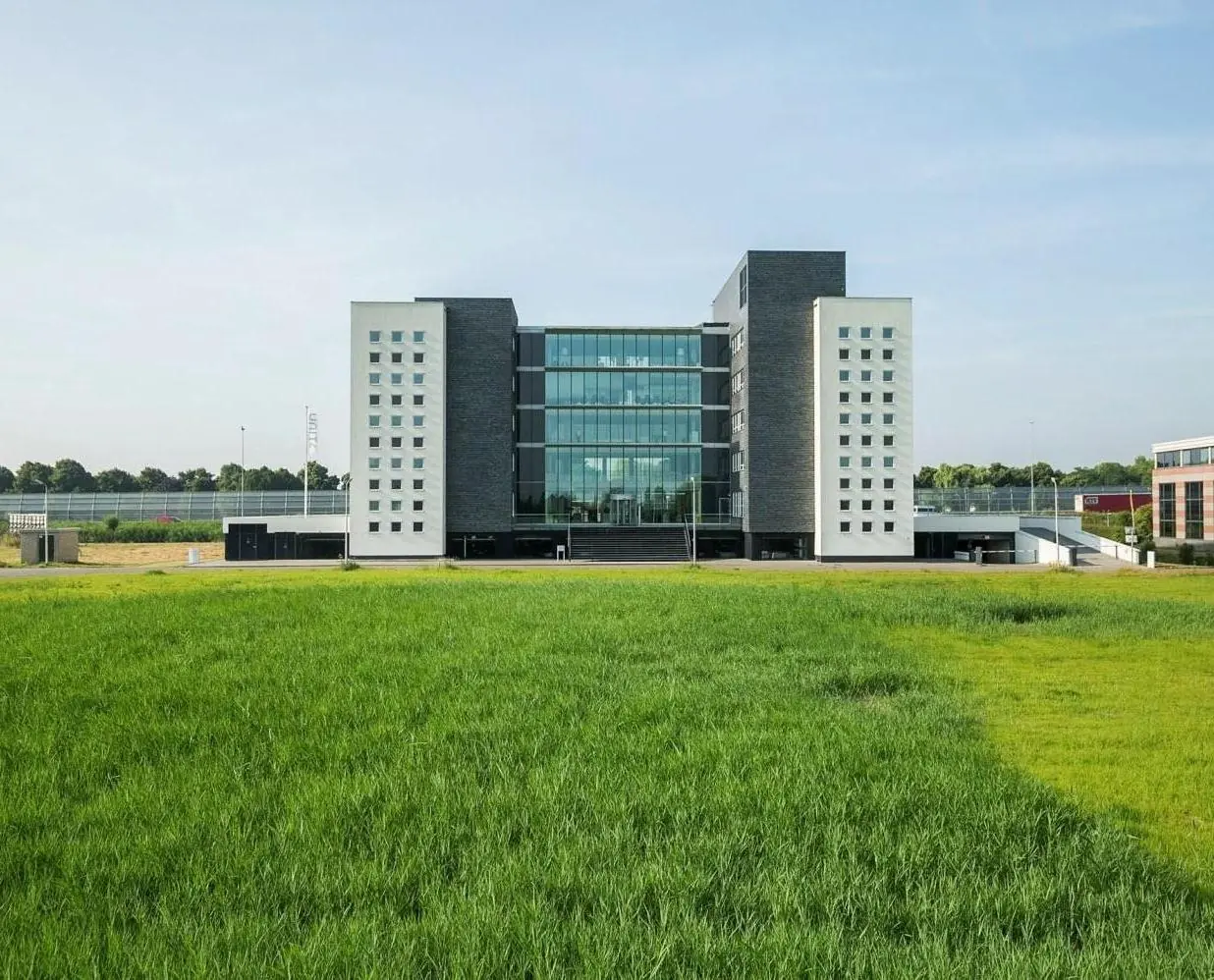 Modern kantoorgebouw Stationspark met glazen gevel, gezien vanaf een groen grasveld.