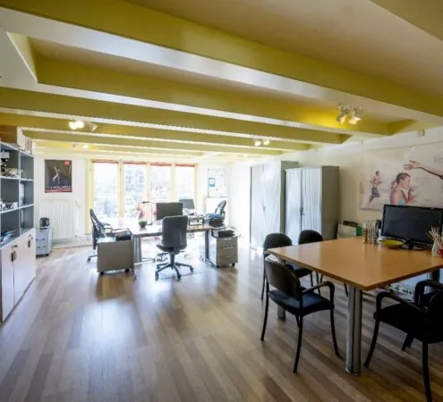 Modern en licht kantoorinterieur aan de Leidsegracht met houten vloer, werkplekken en vergadertafel.