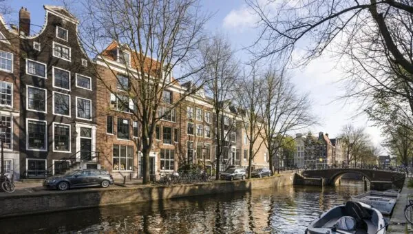 Gracht met klassieke Amsterdamse grachtenpanden en een brug aan de Leidsegracht op een zonnige lentedag.