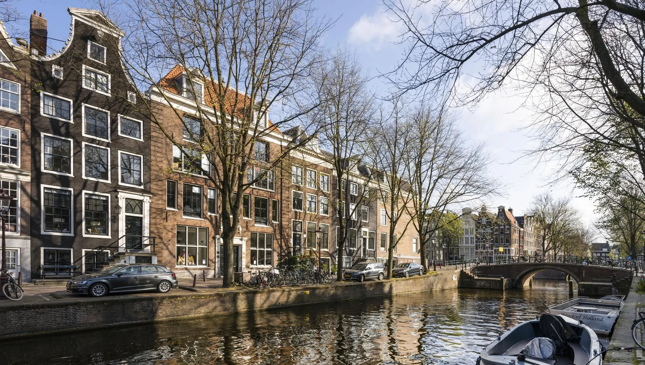 Gracht met klassieke Amsterdamse grachtenpanden en een brug aan de Leidsegracht op een zonnige lentedag.