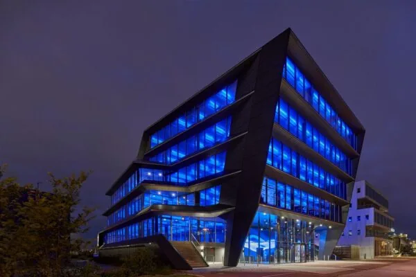Modern kantoorgebouw aan de Moermanskkade in Amsterdam, opvallend verlicht met felblauw licht in de avond.