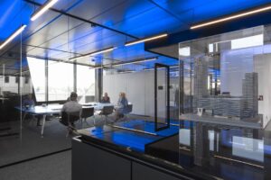 Vergaderruimte met glazen wanden, blauwe plafondverlichting en een maquette van gebouwen aan de Moermanskade.