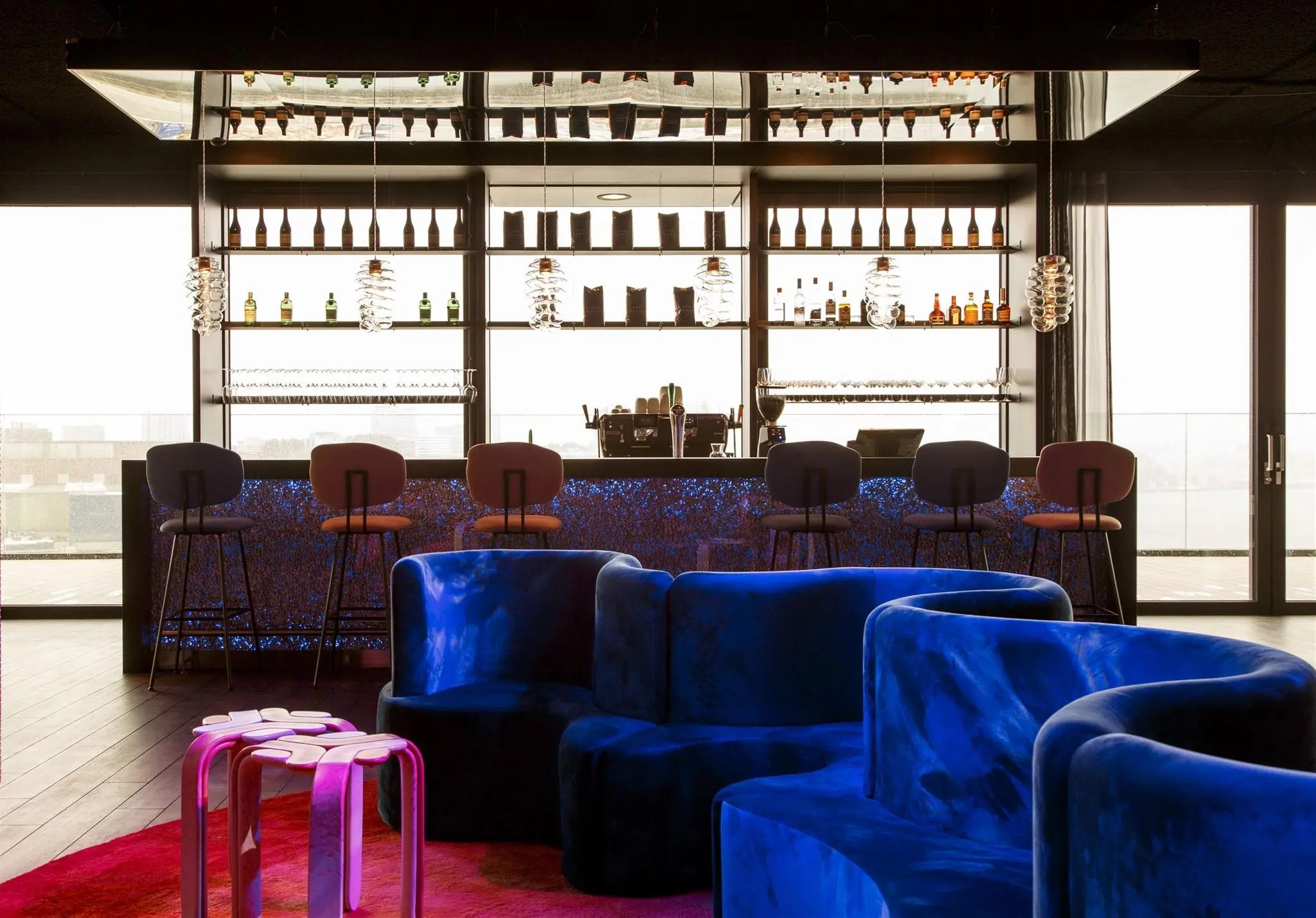 Moderne loungebar aan de Moermanskade met fluwelen blauwe zitbanken, designverlichting en een goed gevulde achterbar.