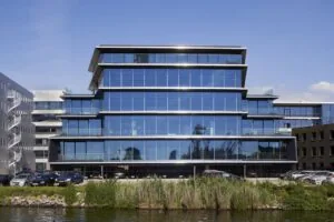 Modern kantoorgebouw met glazen gevel aan de Moermanskkade, gezien vanaf het water.