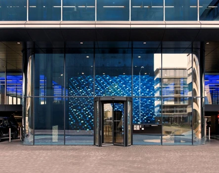 Ingang van een modern kantoorgebouw aan de Moermanskkade met glazen gevel en een opvallende blauw verlichte wand.