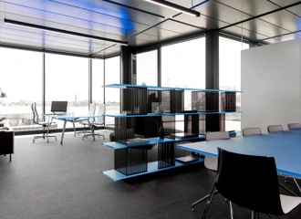 Modern kantoorinterieur aan de Moermanskkade met grote ramen, blauwe accenten en een open werk- en vergaderruimte.