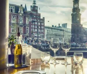 Gedekte restauranttafel met uitzicht op de Reguliersdwarsstraat en de Munttoren in Amsterdam.