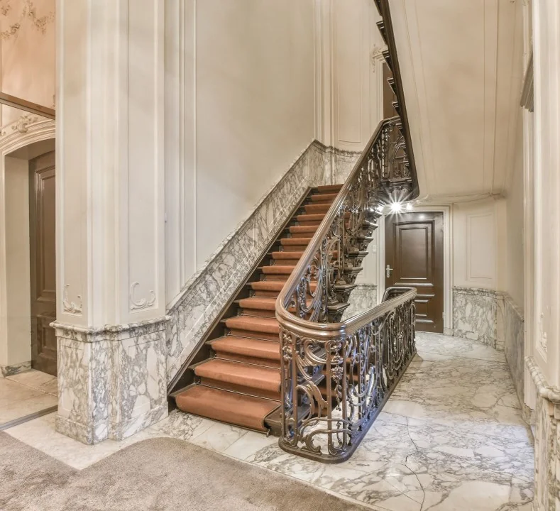 Statige marmeren hal met een klassieke houten trap in een grachtenpand aan de Herengracht.