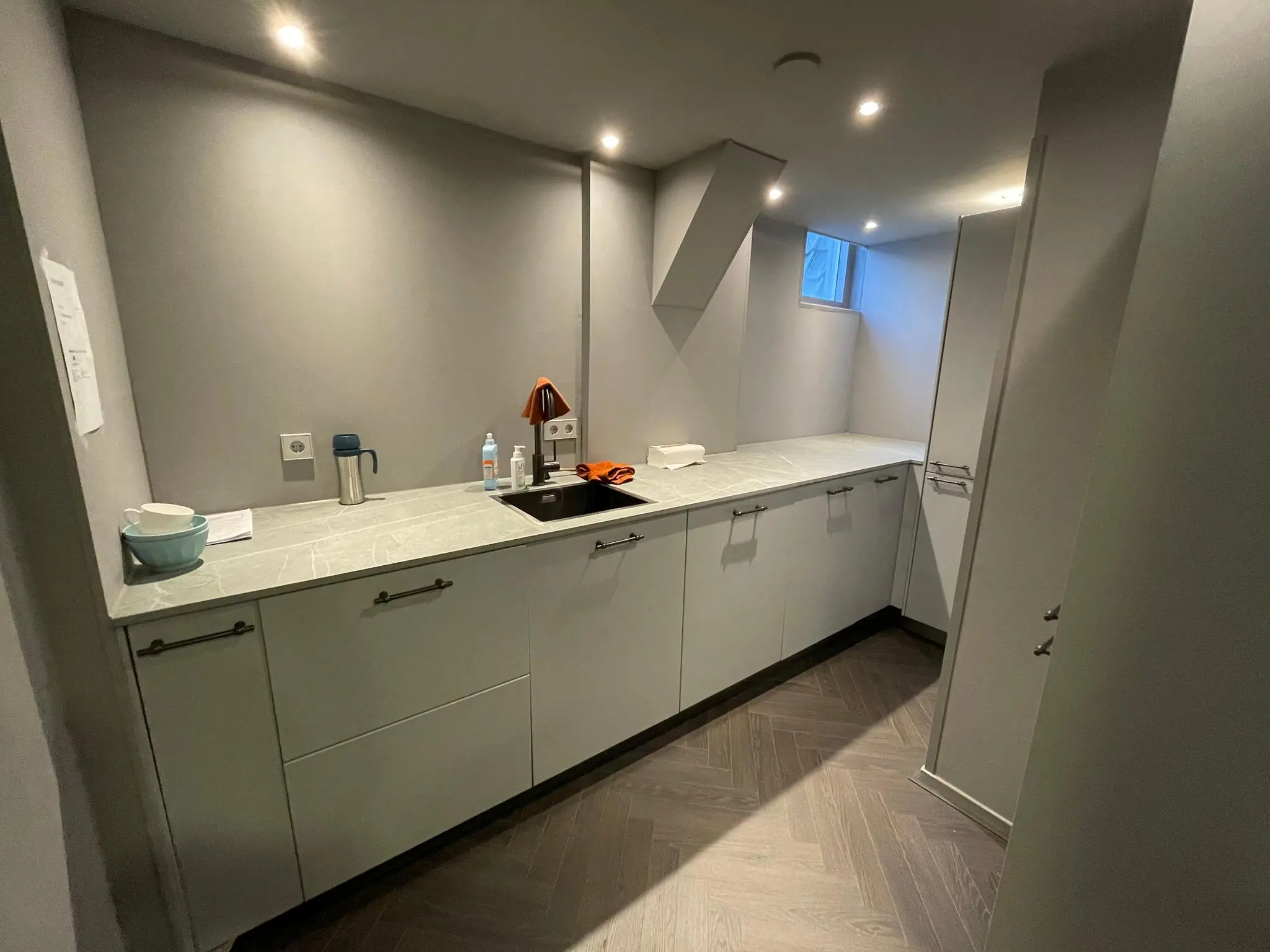 Moderne, smalle grijze keuken met marmeren aanrechtblad en ingebouwd spoelbak aan de Herengracht.