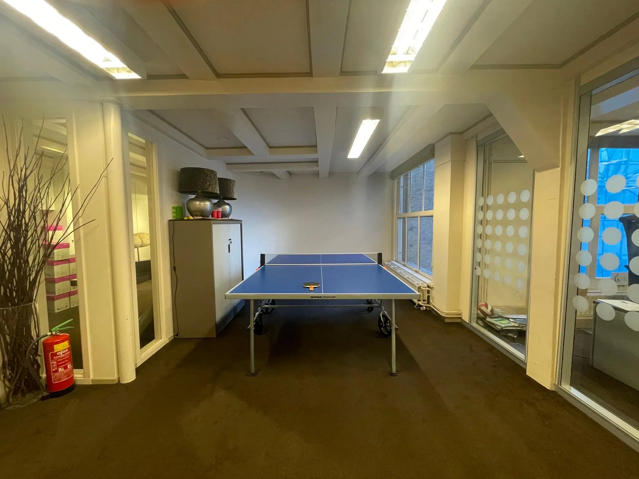 Tafeltennistafel in een kantoorruimte aan de Herengracht met glazen wanden en kasten op de achtergrond.