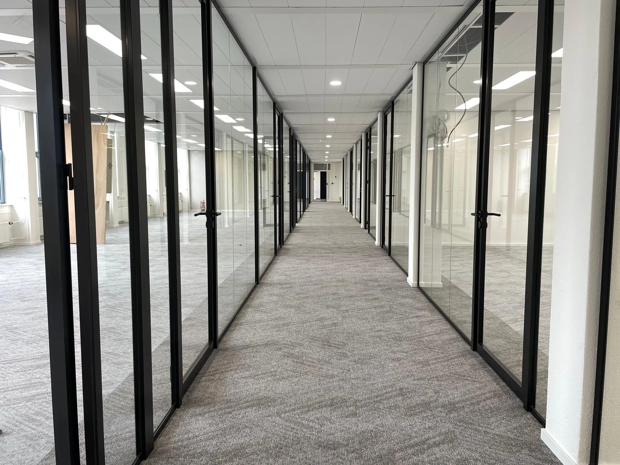 Lange kantoorgang met glazen wanden en deuren in het gebouw aan de Kernkade.