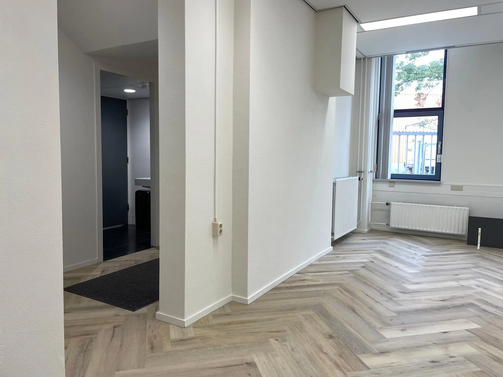 Licht en modern interieur van een kantoorruimte aan de Kernkade met visgraatvloer en grote ramen.