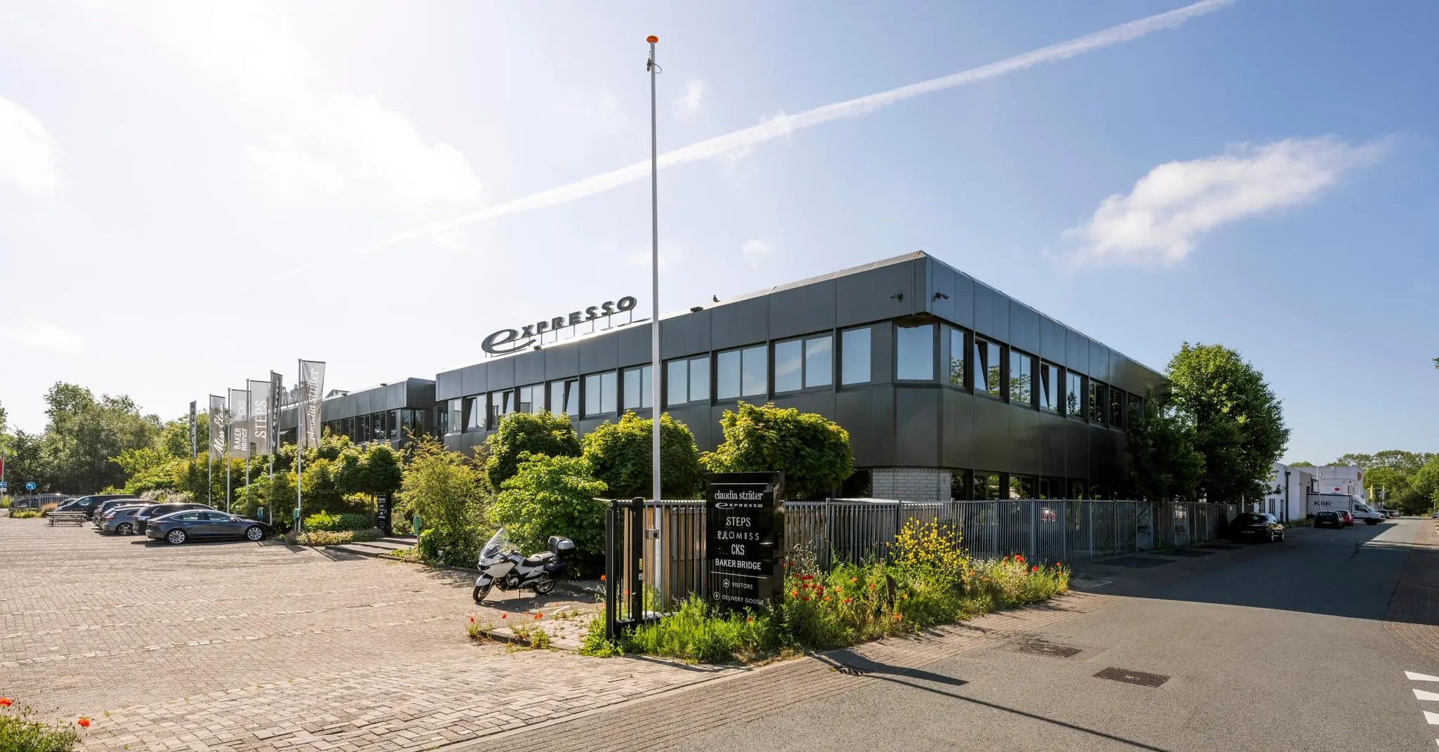 Modern kantoorpand aan de Stammerhove met het logo van Expresso en meerdere modegerelateerde bedrijfsnamen op de gevel en vlaggen.