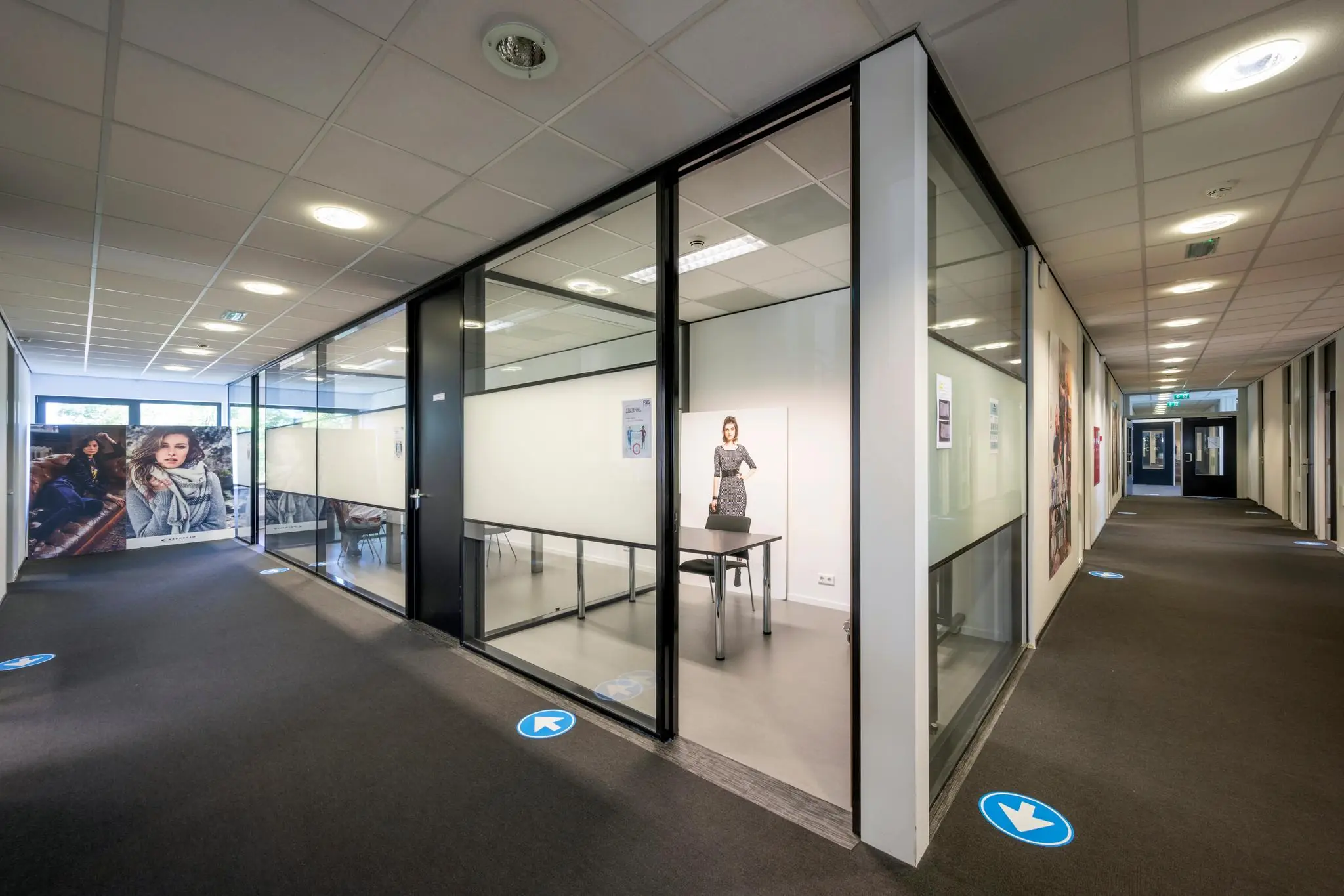 Moderne kantoorruimte in Stammerhove met glazen vergaderruimtes en coronagerelateerde looprichtingspijlen op de vloer.