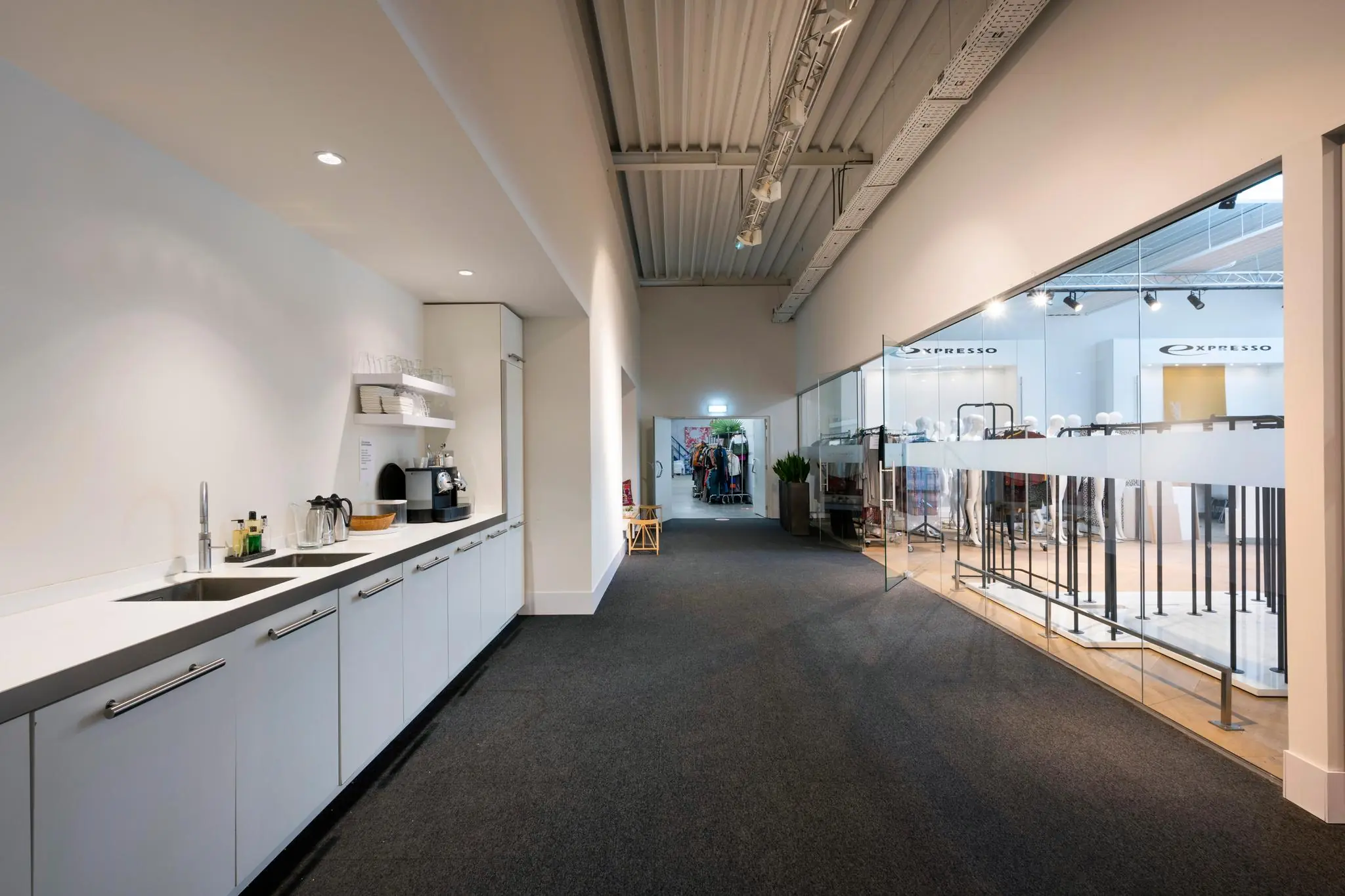 Moderne kantoorruimte met een pantry en een glazen showroom van kledingmerk Expresso.