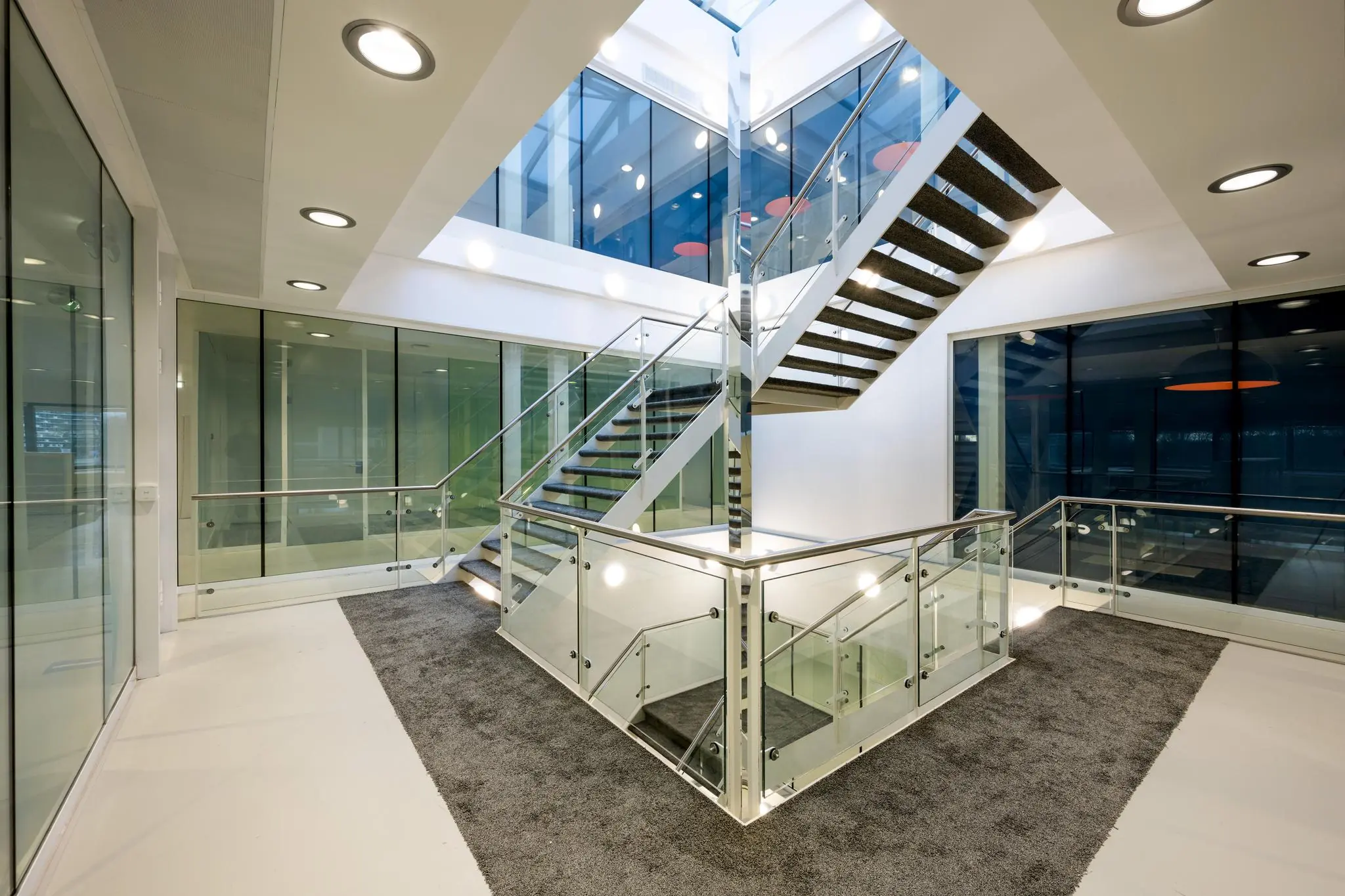 Moderne, lichtovergoten trapopgang met glazen balustrades in een kantoorgebouw aan de Prof. E.M. Meijerslaan.