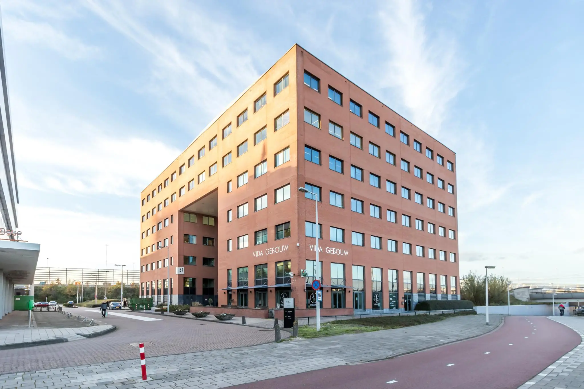 Bakstenen kantoorgebouw genaamd Vida Gebouw aan de Kabelweg in Amsterdam, met meerdere verdiepingen en een doorgang in het midden.