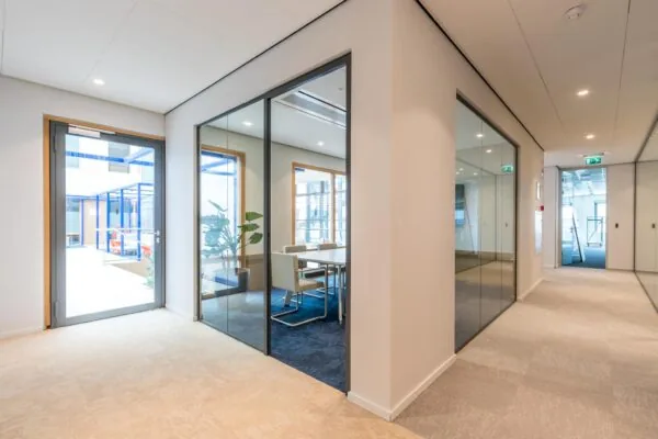 Moderne kantoorruimte aan de Kabelweg met glazen vergaderruimtes en een lichte, open indeling.