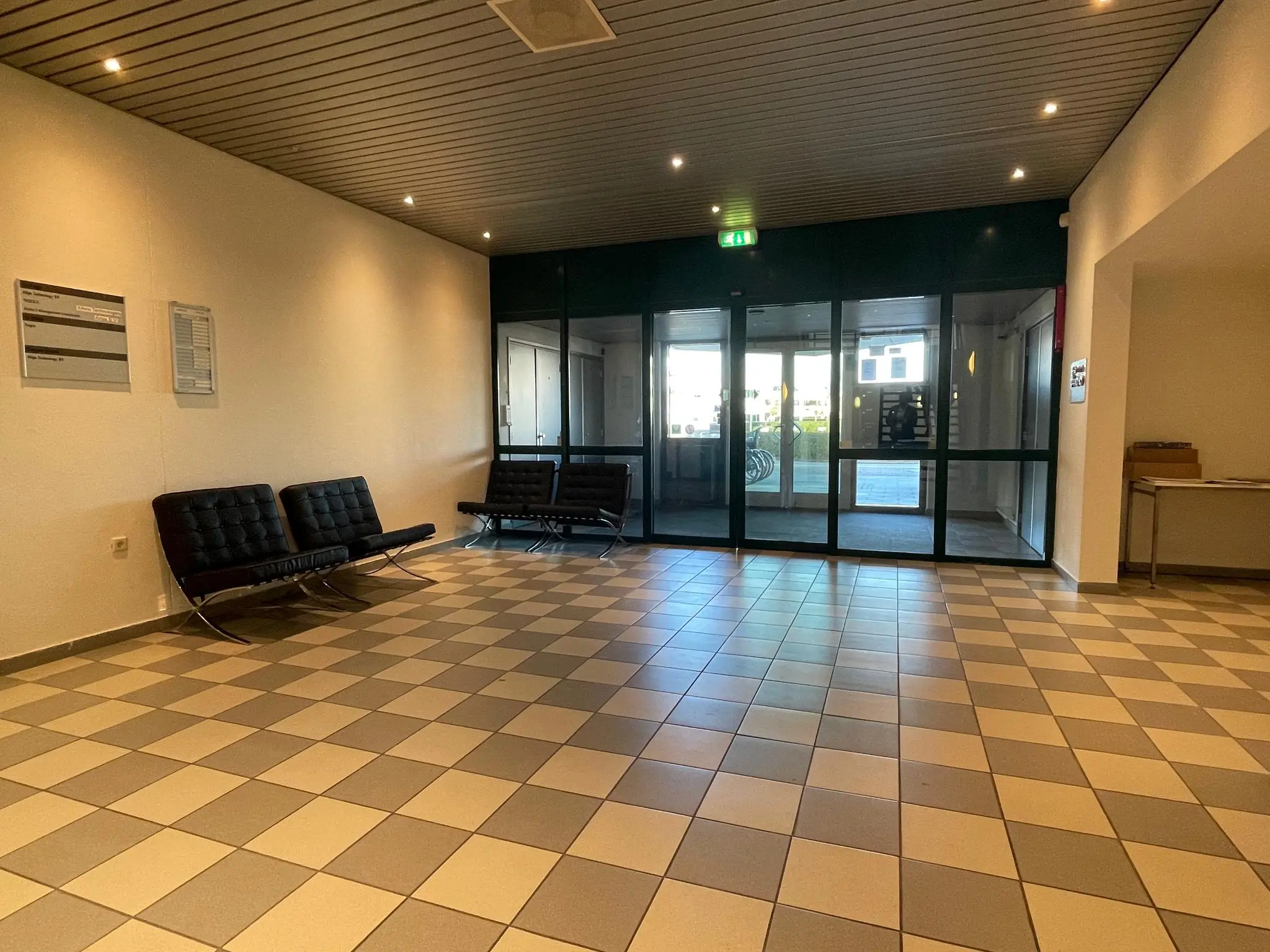 Ingangshal van een kantoorgebouw aan de Zekeringstraat met zwarte stoelen en betegelde vloer.