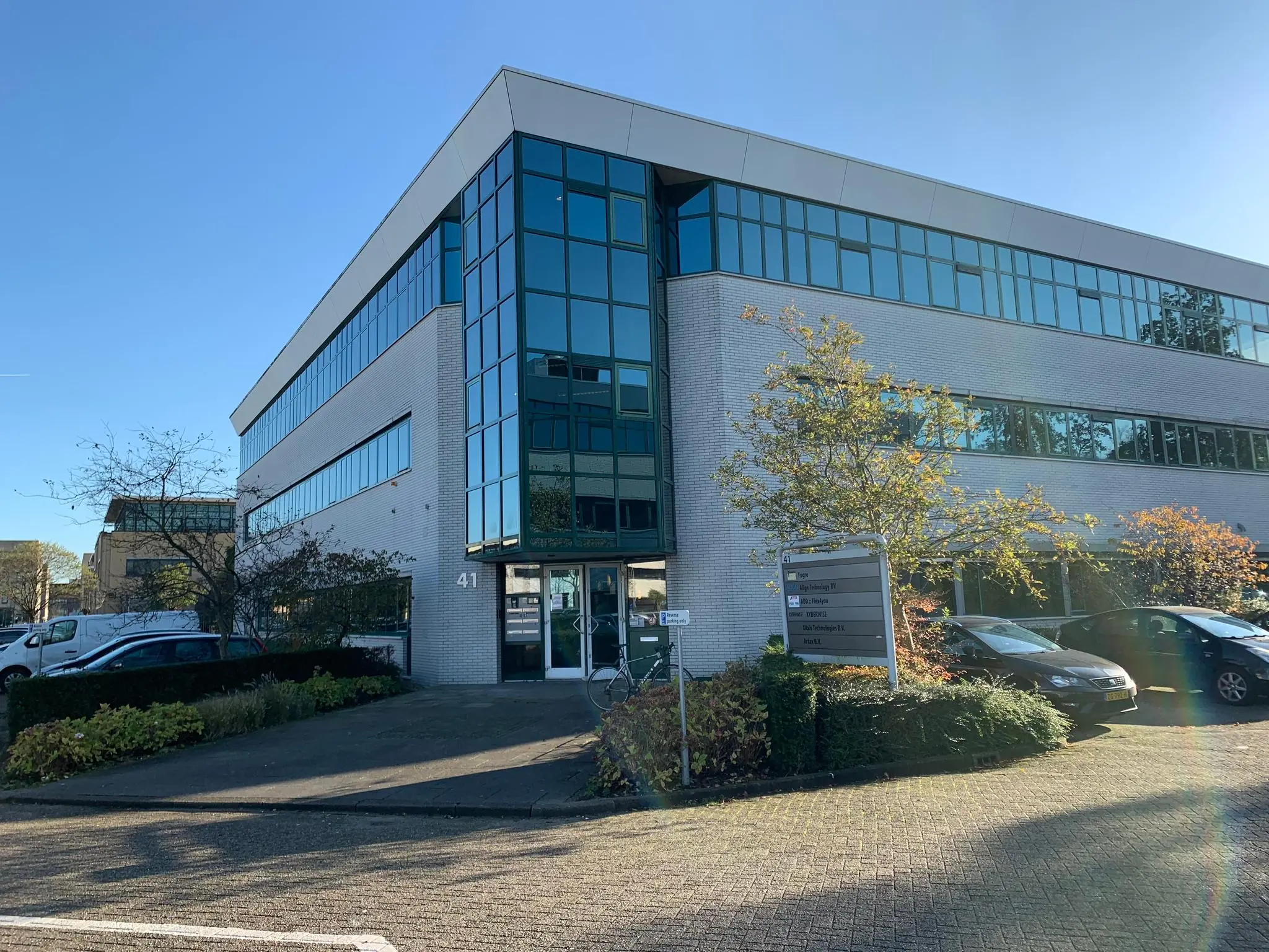 Modern kantoorgebouw aan de Zekeringstraat 41 met glazen gevel en omliggende parkeerplaatsen.