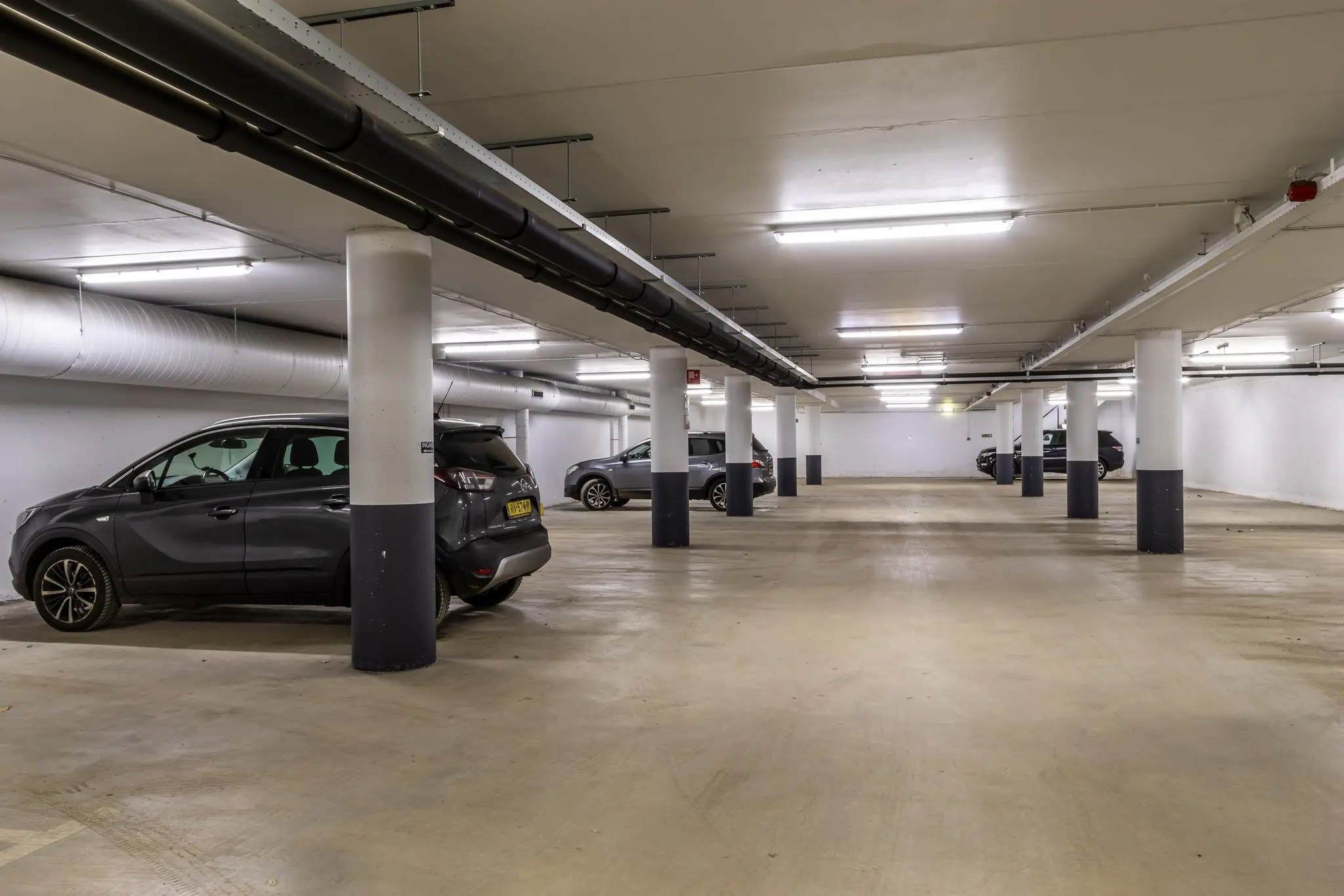 Ondergrondse parkeergarage aan de Oudlaan met enkele geparkeerde auto's en betonnen zuilen.