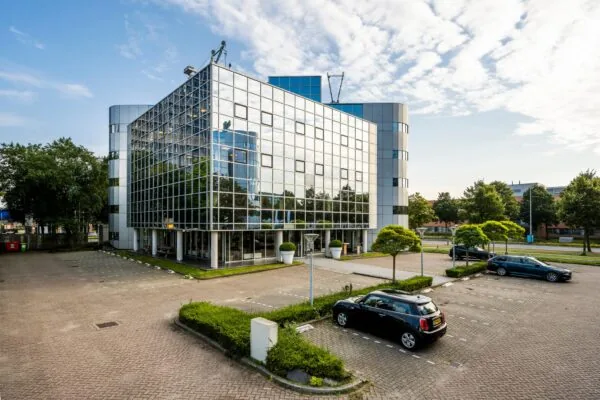 Modern kantoorgebouw aan de Hogehilweg met een glazen gevel en omliggende parkeerplaatsen.