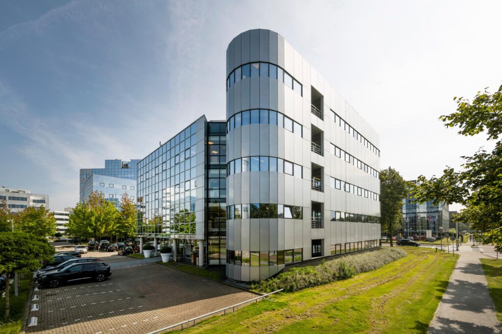Modern kantoorgebouw aan de Hogehilweg in Amsterdam met glazen gevel en omliggende parkeerplaatsen.