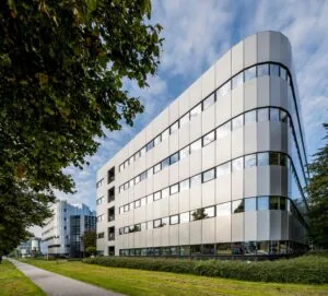 Modern kantoorgebouw aan de Hogehilweg met strakke gevel en reflecterende ramen, omgeven door groen.
