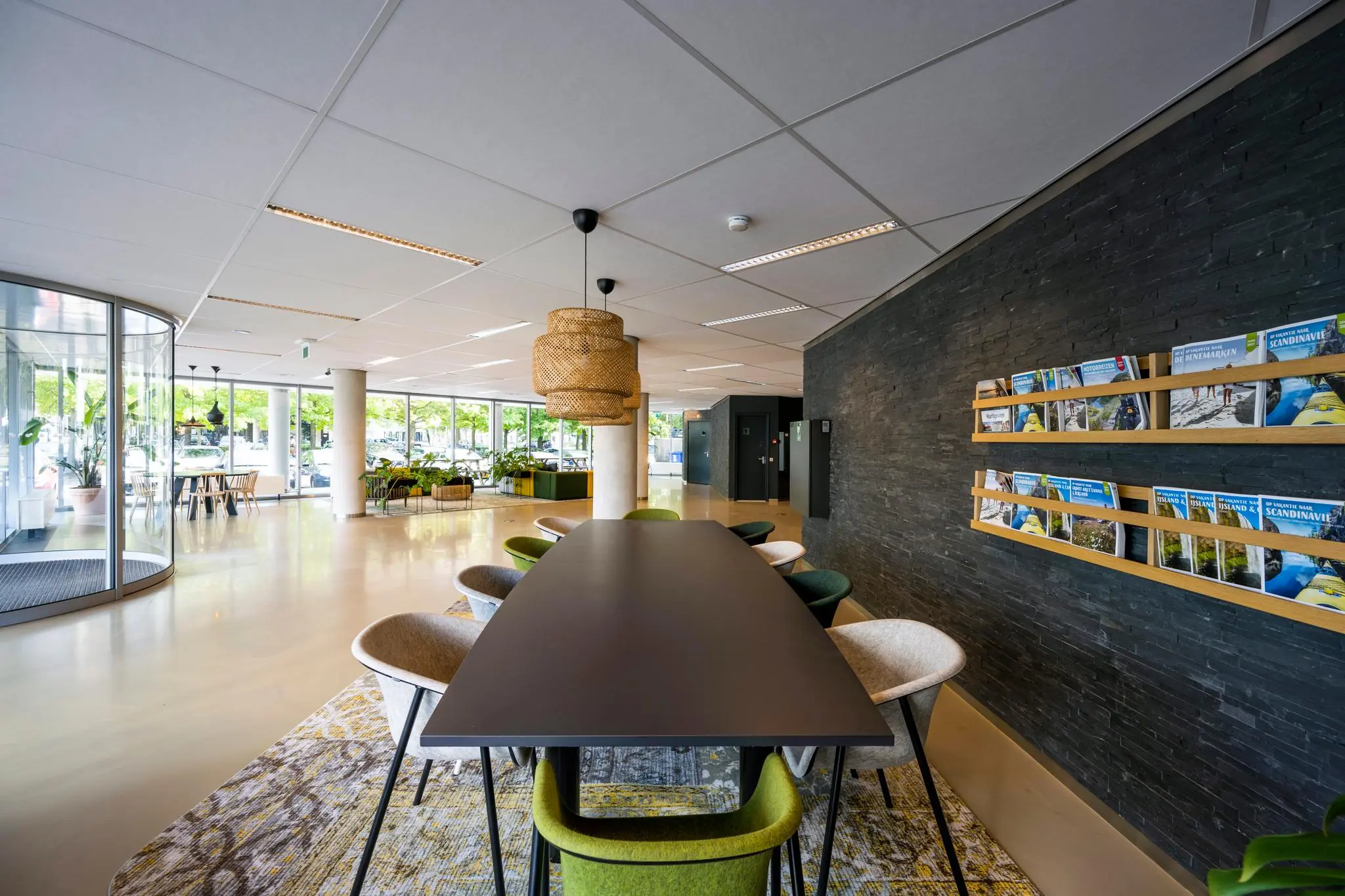 Moderne en lichte ontvangstruimte met een lange vergadertafel, tijdschriftenrek en uitzicht op de straat bij Hogehilweg.