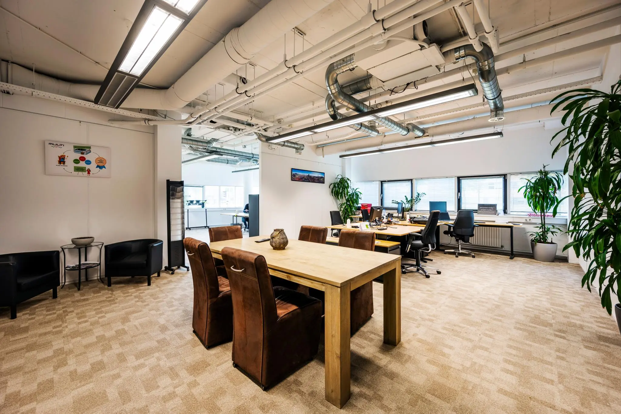 Modern en licht kantoorinterieur aan de Hogehilweg met werkplekken, vergadertafel en veel groen.