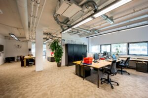 Modern en licht open kantoorinterieur aan de Hogehilweg met bureaus, kasten en zitgedeelte.