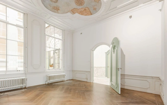 Lichte, klassieke kamer aan de Keizersgracht met visgraatvloer, grote ramen en een plafondschildering.