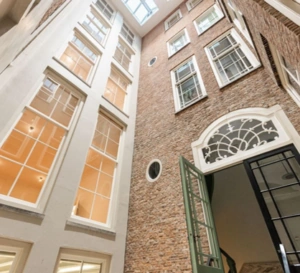 Binnenplaats met hoge bakstenen gevels en grote ramen aan de Keizersgracht in Amsterdam.