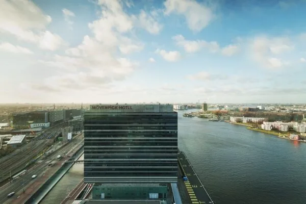 Luchtfoto van het Mövenpick Hotel aan de Piet Heinkade in Amsterdam, met zicht op het IJ en de omliggende stad.