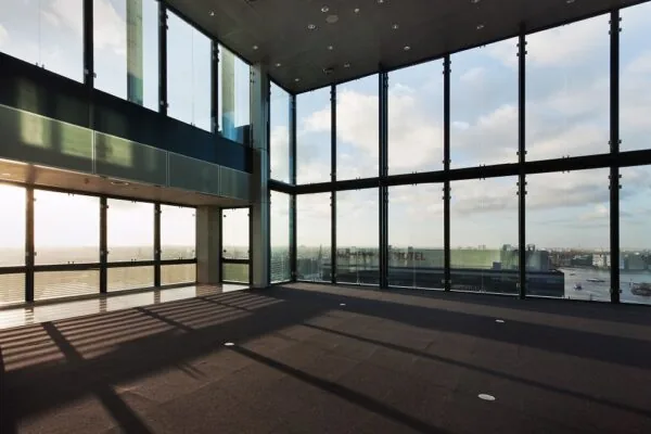 Lichte, lege kantoorruimte met hoge ramen aan de Piet Heinkade met uitzicht op het IJ en het Mövenpick Hotel.