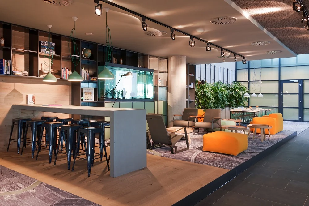 Modern ingerichte lounge- en werkruimte aan de Piet Heinkade met kleurrijke zitplaatsen, hoge tafels en veel natuurlijk licht.