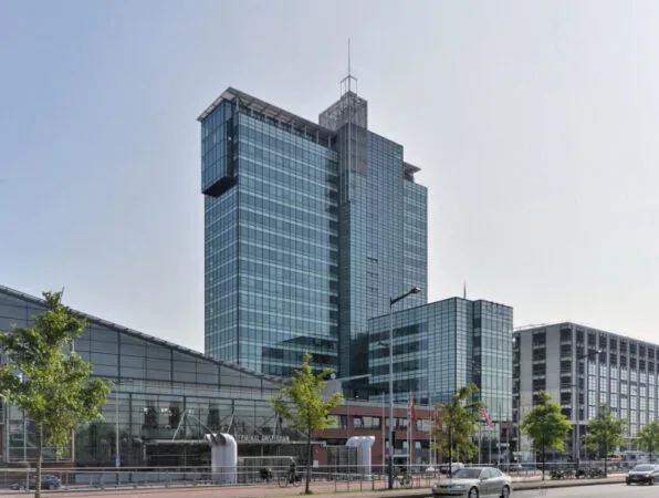 Glazen kantoorgebouw aan de Piet Heinkade in Amsterdam met moderne architectuur en omliggende stadsbebouwing.