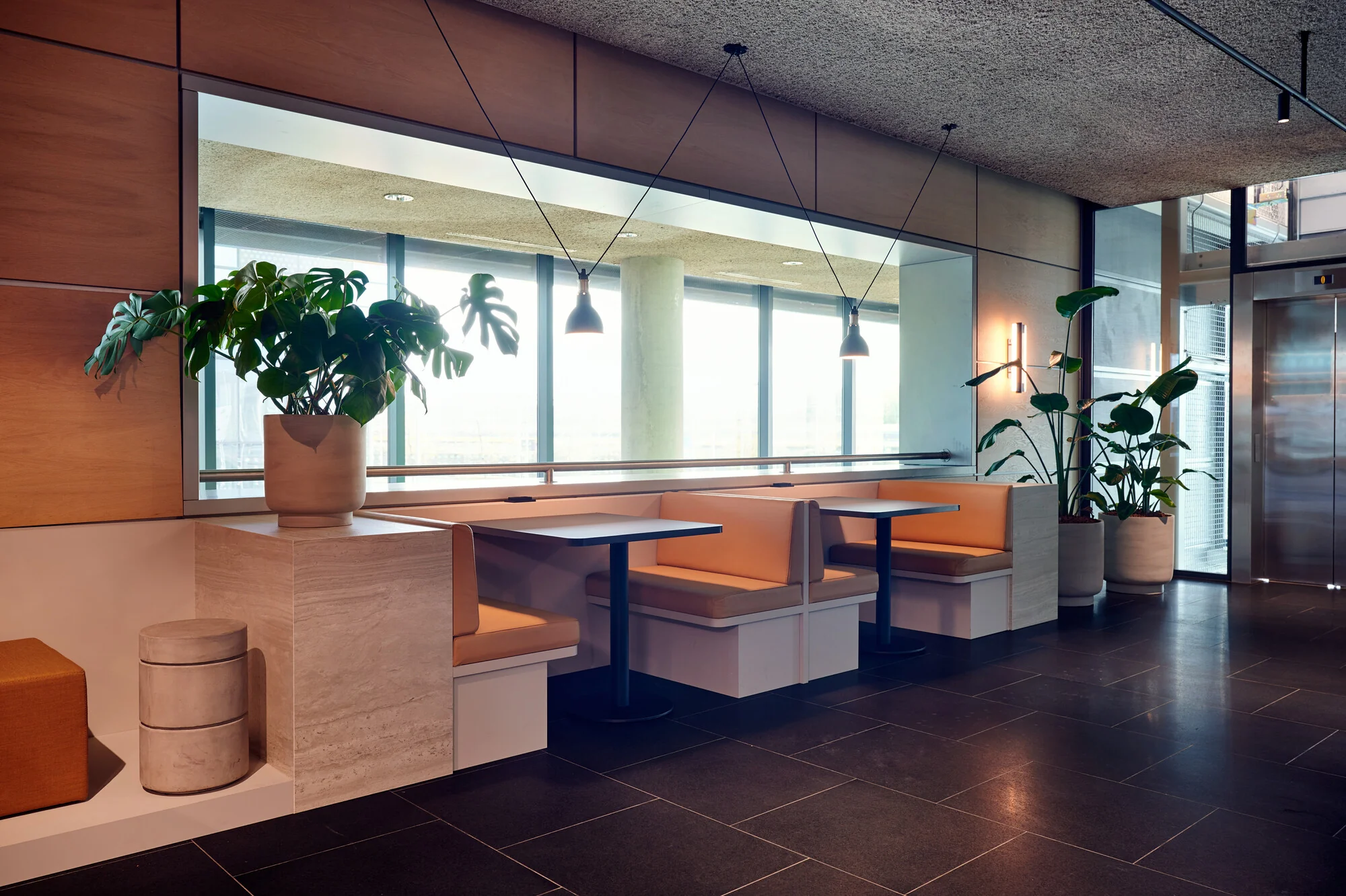 Moderne zithoeken met leren banken en kamerplanten in een kantoorruimte aan de Piet Heinkade.