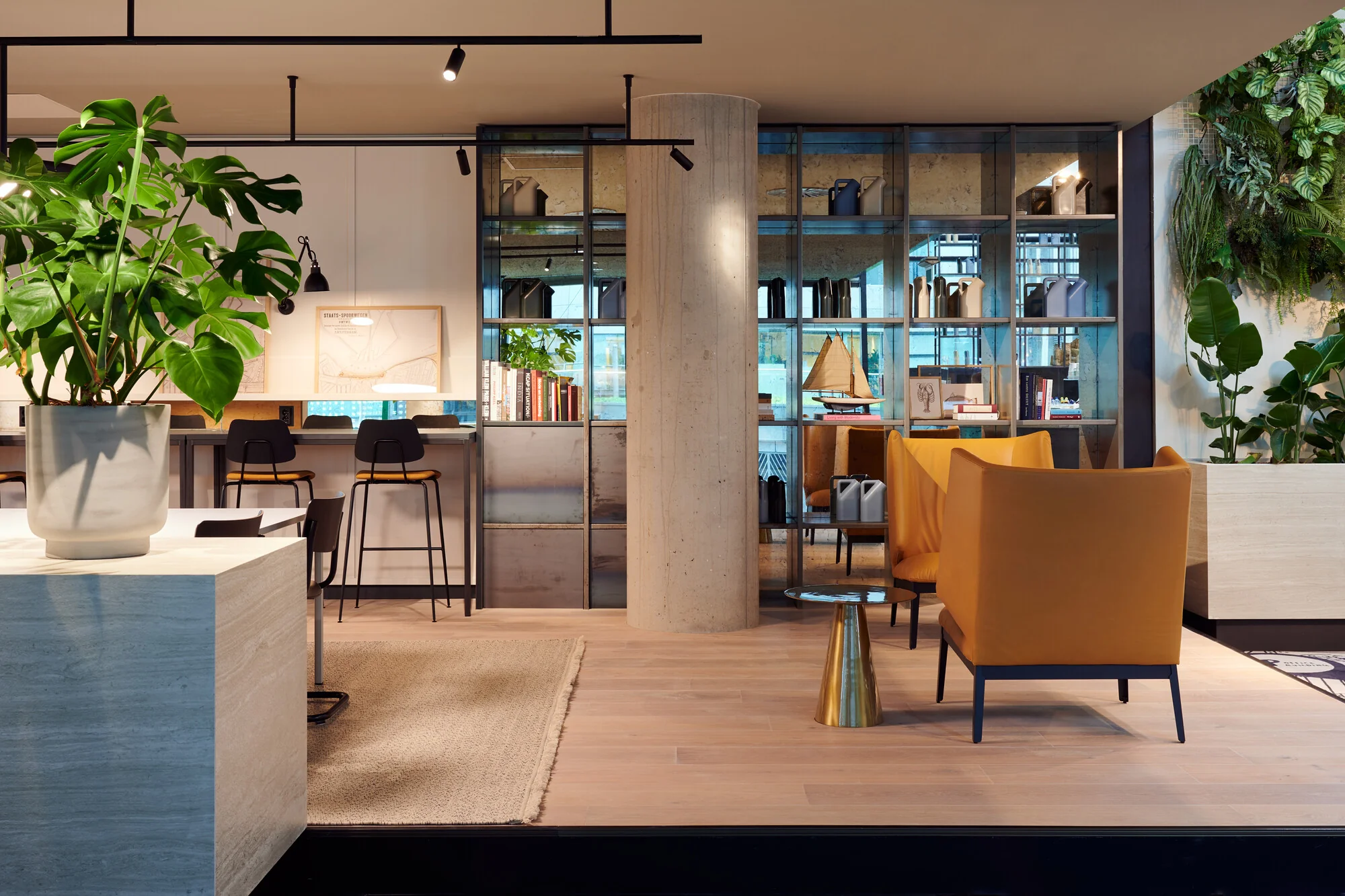 Moderne, sfeervolle lounge- en werkruimte aan de Piet Heinkade met warme houten accenten, planten en een open boekenkast.