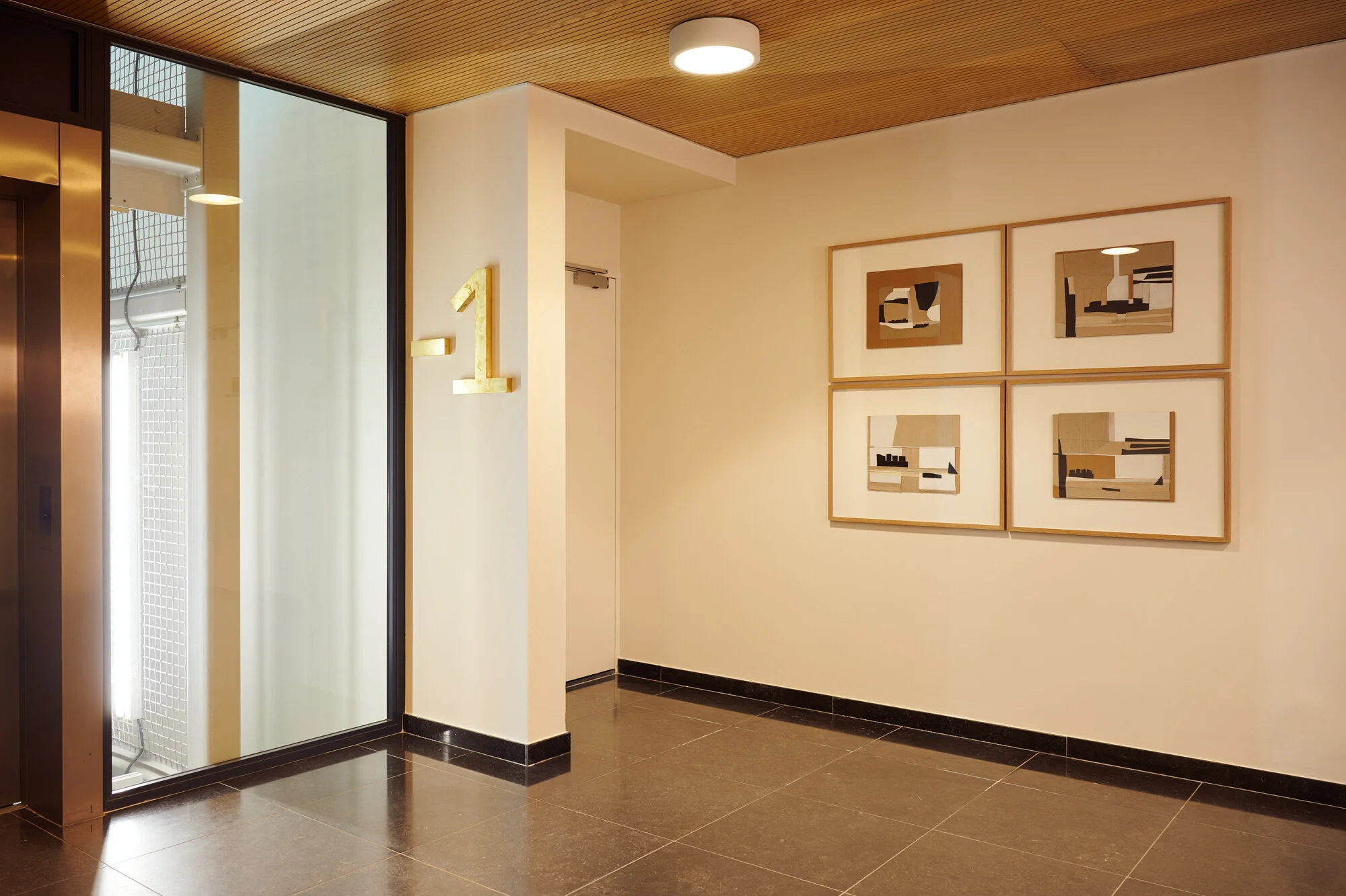 Moderne hal op verdieping -1 van een gebouw aan de Piet Heinkade, met abstracte kunst aan de muur en een liftdeur links.