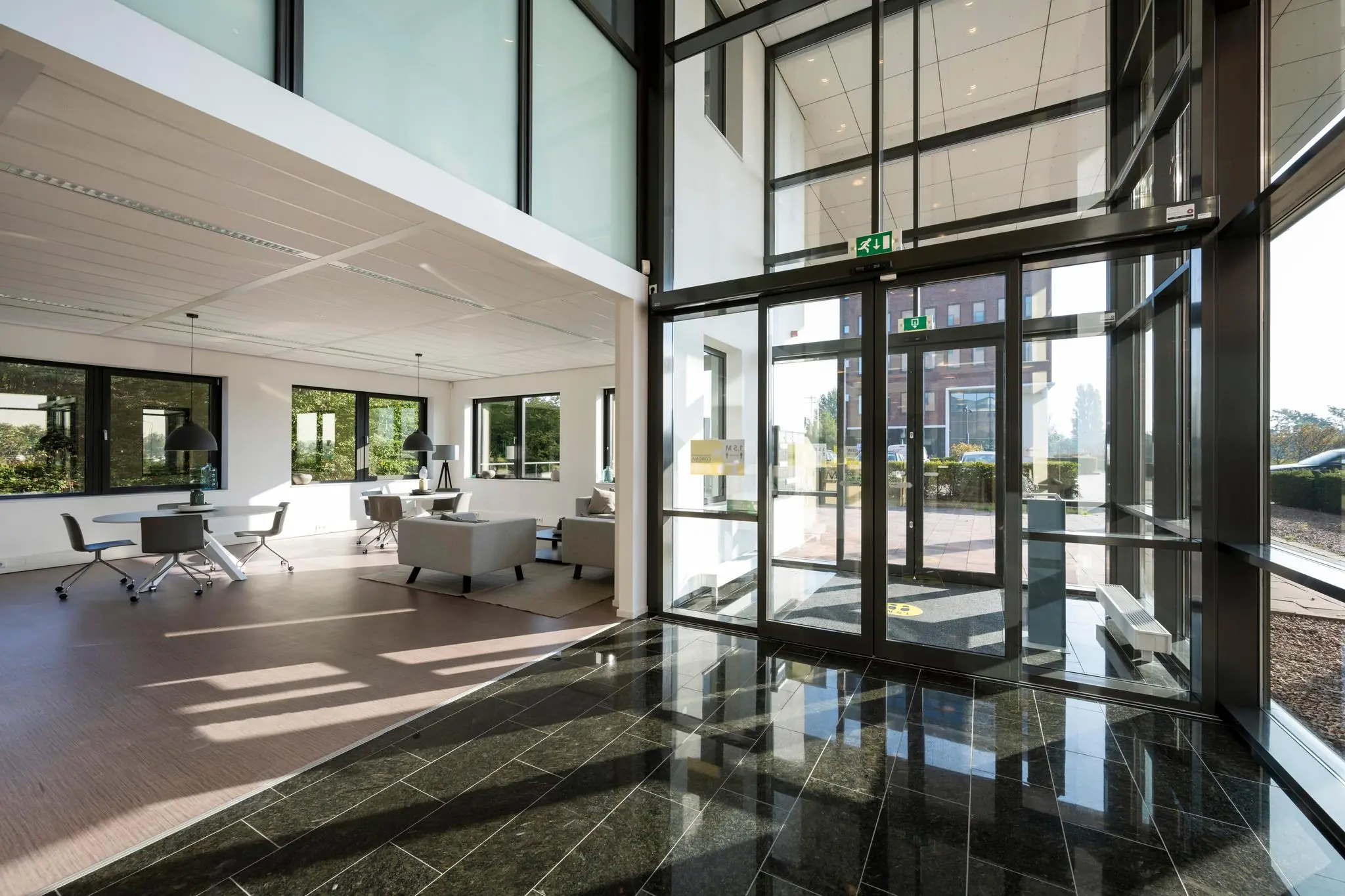 Moderne entreehal met glazen draaideur en aangrenzende open ontvangstruimte aan de Bloemlaan.