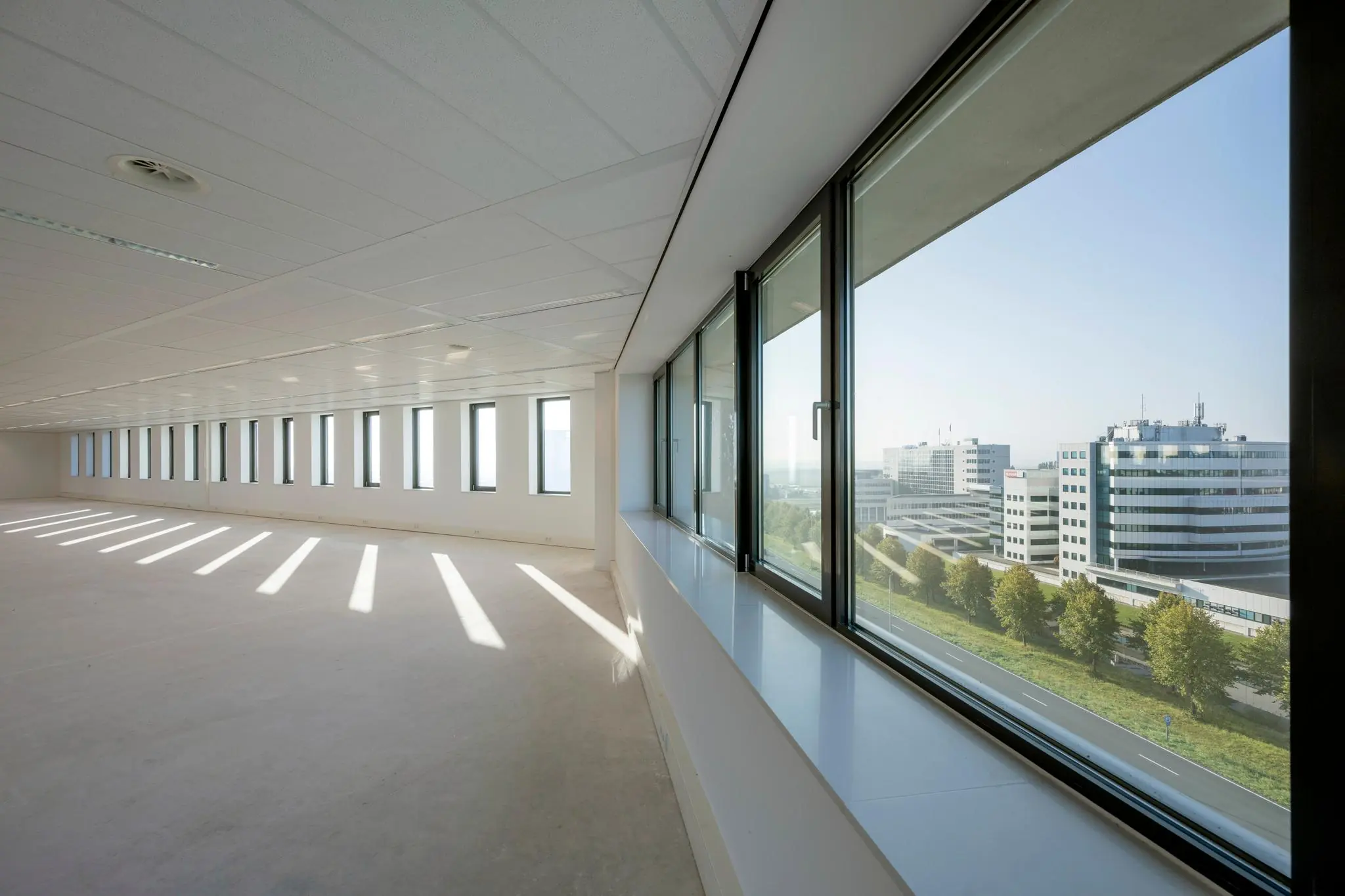 Lichte, lege kantoorruimte aan de Bloemlaan met uitzicht op moderne kantoorgebouwen.