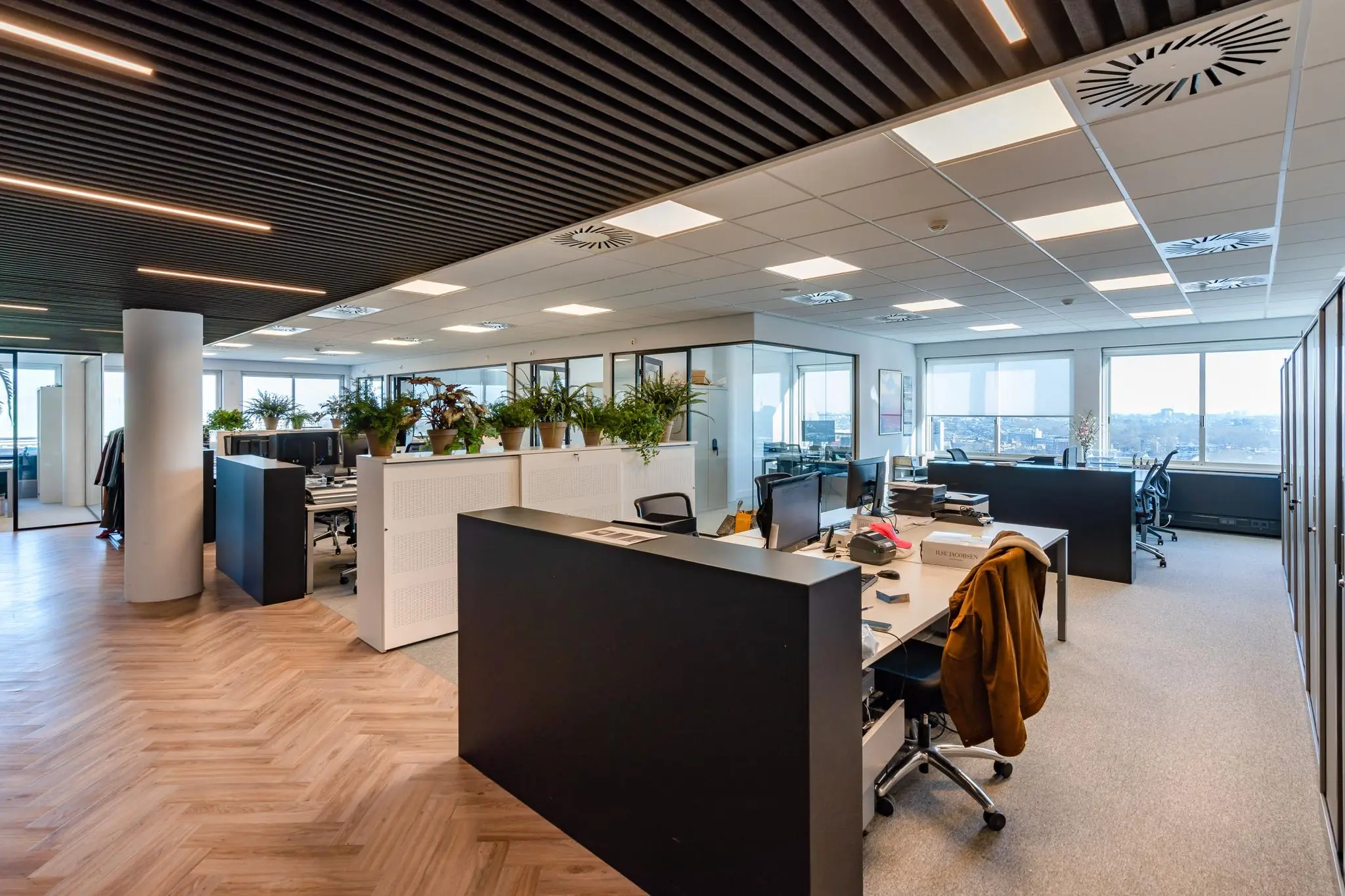 Moderne kantoorruimte aan het Koningin Wilhelminaplein met werkplekken, veel daglicht en planten.