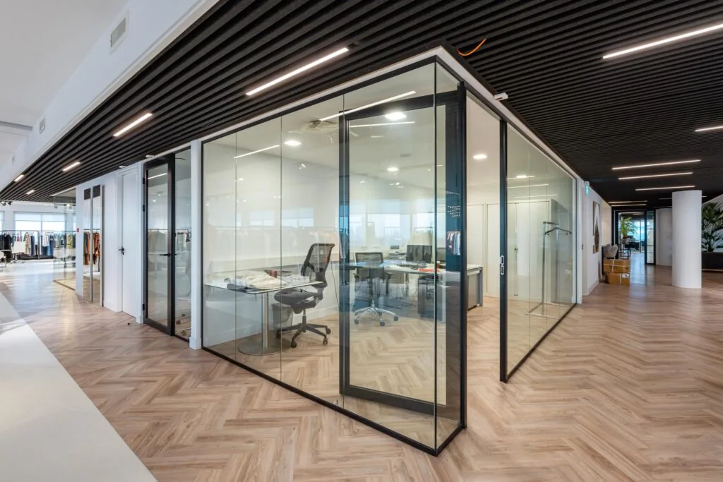Modern kantoorinterieur aan het Koningin Wilhelminaplein met glazen vergaderruimtes en visgraatvloer.