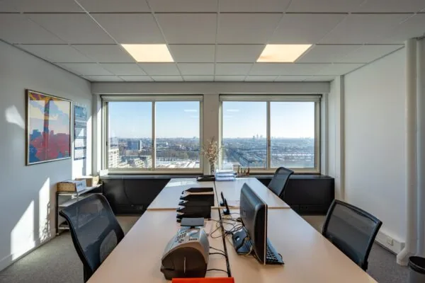 Modern kantoor met werkplekken en uitzicht over het Koningin Wilhelminaplein in Amsterdam.