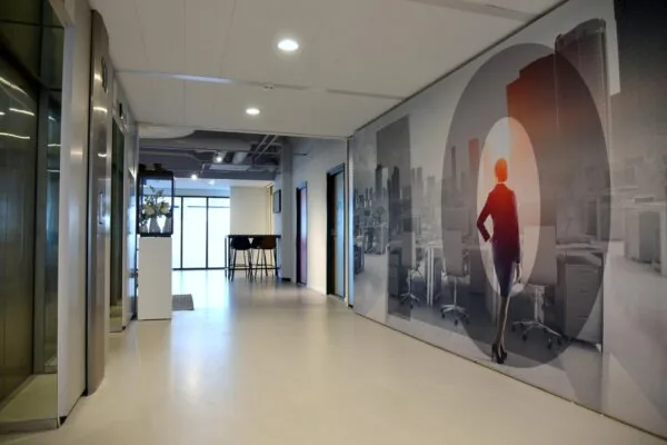 Moderne kantoorhal aan het Koningin Wilhelminaplein met wanddecoratie van een vrouw die uitkijkt over een stadszicht.