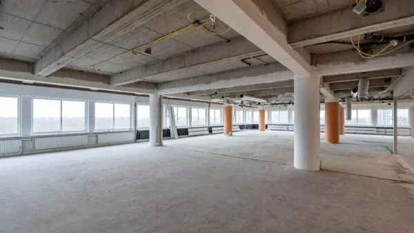 Leegstaand kantoorpand aan het Koningin Wilhelminaplein met zichtbare betonnen plafonds en onafgewerkte vloer.