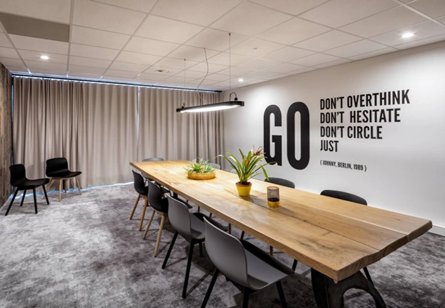 Moderne vergaderruimte aan de Joan Muyskenweg met een lange houten tafel, zwarte stoelen en inspirerende muurquote.