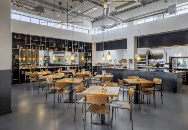 Modern ingerichte bedrijfsrestaurant aan de Joan Muyskenweg met houten meubilair, open keuken en industriële details.