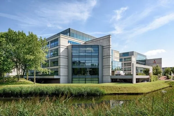 Modern kantoorgebouw aan de Polarisavenue met glazen gevels, omringd door groen en een vijver.